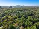 A high-angle shot shows the house surrounded by dense, mature trees with the city skyline in the background at 8 W Andrews Nw Dr, Atlanta, GA 30305
