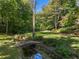Serene backyard featuring a stone bridge over a gentle stream amidst lush greenery at 8 W Andrews Nw Dr, Atlanta, GA 30305