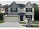 Charming two-story home with brick and gray siding, a manicured lawn, and a two-car garage at 1861 Poplar Falls Ave, Lithonia, GA 30058