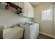 Bright laundry room with washer, dryer, utility sink, storage cabinets, and window at 2121 Rock Court, Loganville, GA 30052