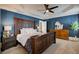 Spacious main bedroom with a wooden bed frame, blue accent wall, and ceiling fan at 4124 Hunt St, Covington, GA 30014