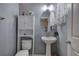 Well-lit bathroom with a pedestal sink, toilet, and storage cabinet at 537 Rendezvous Rd, Acworth, GA 30102