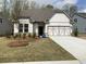 Charming single-story home featuring a two-car garage, manicured lawn, and inviting front entrance at 76 Mayhaw Pt, Sharpsburg, GA 30277