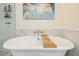 Close up of bathroom soaking tub featuring marble wall surround, modern faucet, and a wood tray at 195 14Th Ne St # Ph206, Atlanta, GA 30309