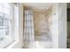 Bright bathroom featuring a shower-tub combo with beige stone tile and a white and gray curtain at 195 14Th Ne St # Ph206, Atlanta, GA 30309