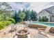 Inviting backyard featuring a stone patio with fire pit and relaxing adirondack chairs overlooking the pool at 3541 Haddon Hall Dr, Buford, GA 30519