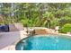 Backyard pool area with a waterfall feature, lush landscaping, and a tranquil setting at 3541 Haddon Hall Dr, Buford, GA 30519