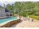 Resort style stone patio with a pool, outdoor seating, fire pit, and lush landscaping creating a private oasis at 3541 Haddon Hall Dr, Buford, GA 30519