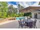 Poolside patio with an outdoor dining table under an umbrella next to the large in ground pool at 3541 Haddon Hall Dr, Buford, GA 30519