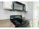 Close-up of kitchen electric range and microwave with white hexagonal tile backsplash and light countertops at 809 Brickleridge Se Ln, Mableton, GA 30126