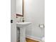 A half-bath featuring a pedestal sink and wooden framed mirror, offering a blend of classic and modern design at 306 Atley Pl, Alpharetta, GA 30009