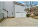 Two car garage with ample parking space on concrete driveway and lush tree providing shade at 4845 Weathervane Dr, Alpharetta, GA 30022