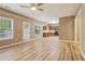 Bright living room with wood floors, ceiling fan, and adjacent kitchen, offering an open layout at 4845 Weathervane Dr, Alpharetta, GA 30022