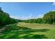 Expansive green golf course with players visible in the distance, backed by a beautiful treeline under a bright sky at 525 Sycamore Pt, Woodstock, GA 30189