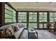A comfy screened porch features a plush sofa and a view of the surrounding trees at 525 Sycamore Pt, Woodstock, GA 30189