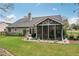 Backyard view of a gray house, showing the screened-in porch and stone paver patio, all surrounded by green grass at 1145 Prospect Mill Dr, Lawrenceville, GA 30043
