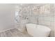 Modern bathroom featuring marble tile shower, soaking tub, and large window with wooded view at 508 Sutters Mill Rd, Stone Mountain, GA 30087