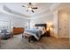 Cozy main bedroom features tray ceiling, ceiling fan, dresser and chair at 4405 Croftshire Pl, Cumming, GA 30040