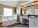 Bright bathroom featuring a soaking tub, window, and a double vanity with gray cabinets at 7937 Habanera Ln, Lithonia, GA 30058
