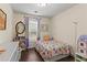 A charming bedroom with a colorful floral-themed bed, a large window, and a playful dollhouse at 4829 Thicket Nw Path, Acworth, GA 30102