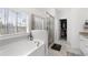 Luxurious bathroom with a soaking tub, glass-enclosed shower, and walk-in closet access at 7500 Gillespie Pl, Douglasville, GA 30135