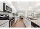 Open kitchen with white cabinets, stainless appliances, granite counters, and a view of the dining area at 7500 Gillespie Pl, Douglasville, GA 30135