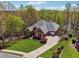 Aerial view of a brick home with lush landscaping and a long driveway at 6060 Masters Club Dr, Suwanee, GA 30024