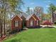 Brick home featuring a manicured lawn and mature trees surrounding the property at 6060 Masters Club Dr, Suwanee, GA 30024