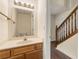 Bathroom featuring wooden cabinets, white countertops, and a staircase adjacent to a half bath at 9992 Neuchatel Cres, Jonesboro, GA 30238