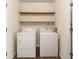 Functional laundry room featuring a washer, dryer, and open shelving for convenient storage at 9992 Neuchatel Cres, Jonesboro, GA 30238