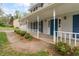 Inviting front porch with white railing, blue door, and manicured greenery at 9992 Neuchatel Cres, Jonesboro, GA 30238