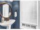 Charming powder room features pedestal sink, round mirror, blue walls, and window with blinds at 1829 Appaloosa Mill Ct, Buford, GA 30519