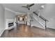 Open-concept living room with a marble fireplace, wood-look floors, ceiling fan, and staircase at 5987 Turfway Park Ct, Sugar Hill, GA 30518