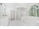 This elegant bathroom boasts granite counters, white cabinets, tile floors, and soaking tub under a decorative window at 545 Slane Trce, Roswell, GA 30076