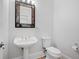 A half-bathroom with a pedestal sink, elegant mirror, and classic fixtures at 545 Slane Trce, Roswell, GA 30076