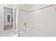 White bathroom has a tiled shower over tub, white tiling, and view to adjoining room at 545 Slane Trce, Roswell, GA 30076