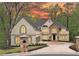 Stunning two-story stucco home featuring a stone accent wall, manicured lawn, and driveway leading to the three-car garage at 545 Slane Trce, Roswell, GA 30076