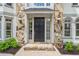 Close-up of the home's front door with sidelights and transom window, stone entryway, and decorative outdoor lighting at 545 Slane Trce, Roswell, GA 30076