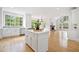 An open-concept kitchen with a center island flowing into the living area and its stone fireplace at 545 Slane Trce, Roswell, GA 30076