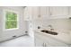Bright laundry room features a utility sink, white cabinets, and a window with a view of the lush greenery outside at 545 Slane Trce, Roswell, GA 30076