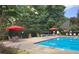 Refreshing pool area featuring comfortable seating, umbrellas, a diving board, and lush greenery for an inviting summer scene at 545 Slane Trce, Roswell, GA 30076