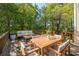 Wooden backyard deck with a dining table, couch, and view of the woods at 904 Little River Ln, Woodstock, GA 30189