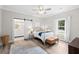 Bright bedroom boasts a ceiling fan, neutral walls, and bathroom access through a modern barn door at 13 E Palmetto St, Porterdale, GA 30014