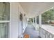 A cozy front porch features a wood deck, white railings, and natural decor at 13 E Palmetto St, Porterdale, GA 30014
