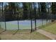 A fenced tennis court featuring a blue and green surface and surrounded by lush greenery at 3097 Sycamore Ln, Marietta, GA 30066