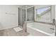 Bright bathroom featuring a tub, shower, and a view of the yard outside at 1895 Weston Ln, Tucker, GA 30084