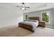Spacious bedroom with a king-size bed, tray ceiling, and natural light from the two windows at 1895 Weston Ln, Tucker, GA 30084