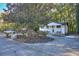 Charming home exterior featuring a circular driveway, mature trees, and landscaped flower beds at 921 Creekdale Dr, Clarkston, GA 30021