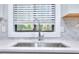 Close-up of kitchen sink and faucet with white countertops, tile backsplash, and a bright window at 921 Creekdale Dr, Clarkston, GA 30021