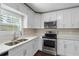 Well-lit kitchen featuring white cabinets, stainless steel appliances, and a double basin sink beneath a window at 3309 Poplar Dr, Lawrenceville, GA 30044